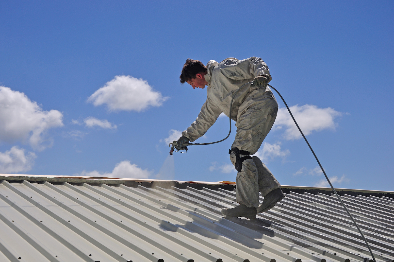 man on roof coating